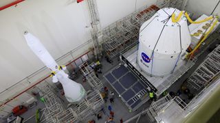 Engineers install the launch abort system on the Orion space capsule that will fly unmanned to the moon later this year.