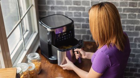 Woman opening air fryer drawer