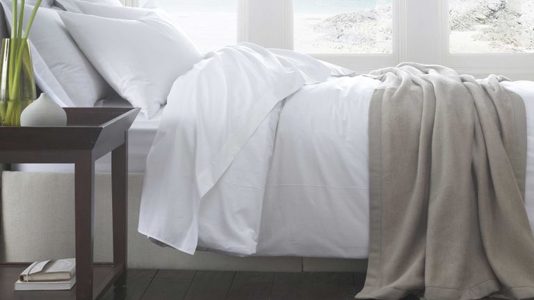 white bedding on double bed with fitted sheet and blanket