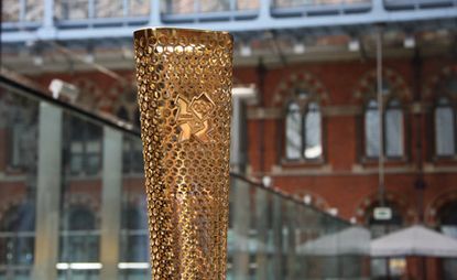 Gold, triangular torch with 8000 holes and featuring the Olympic logo