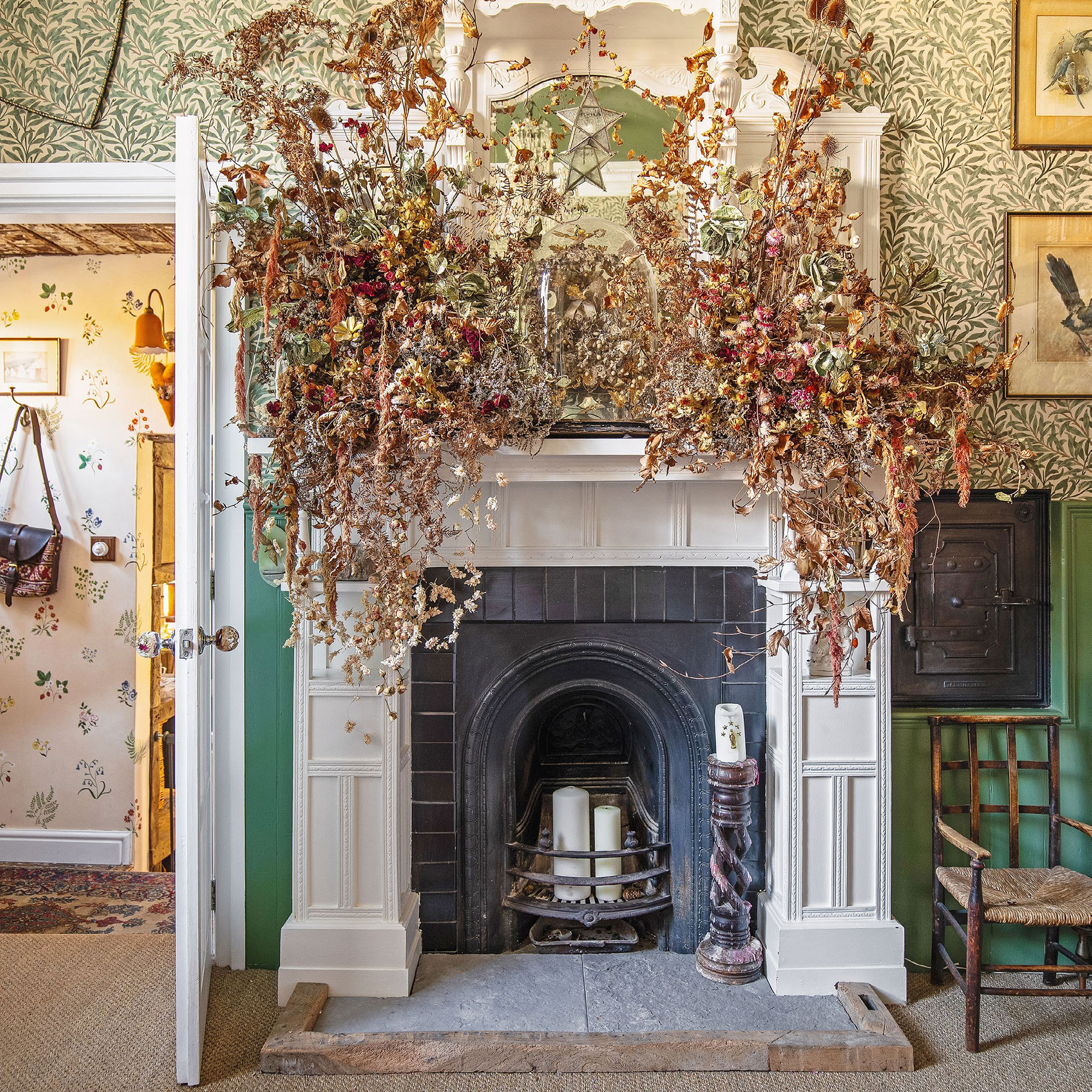 Fireplace in room with botanical wallpaper and mantle covered in dried flower arrangements.