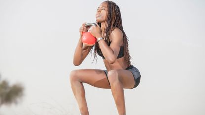 Woman performs a kettlebell squat