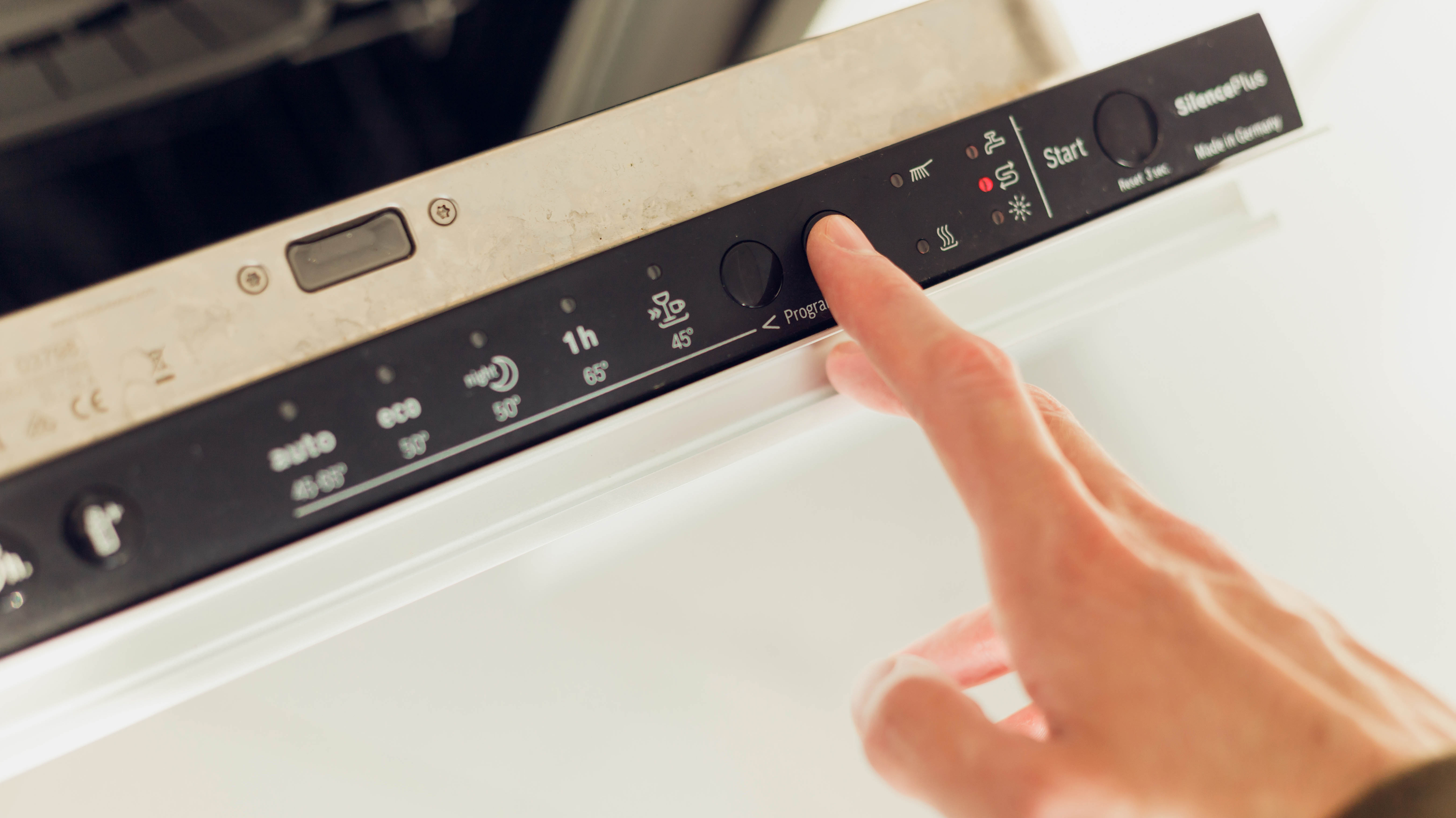 Someone selecting a program on a dishwasher control panel