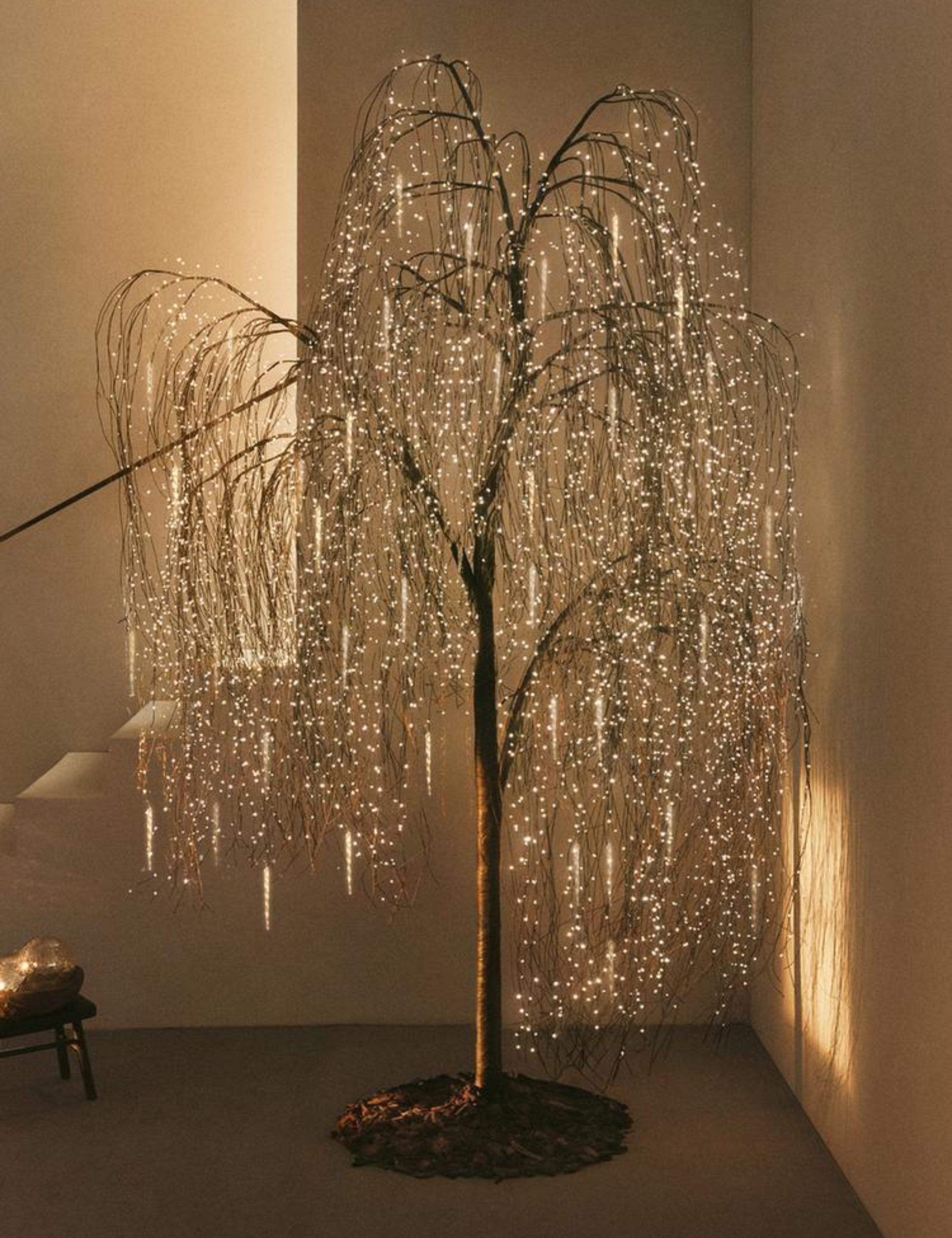 Whimsical twinkling twig tree pictured in a sleek entryway area