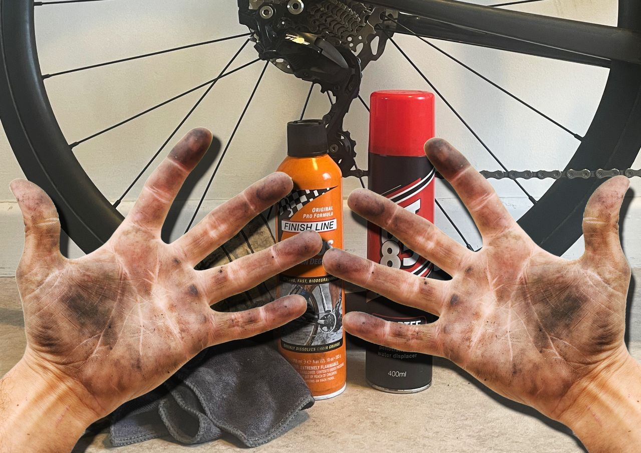 Oily hands with a bicycle wheel and cleaning products in the background