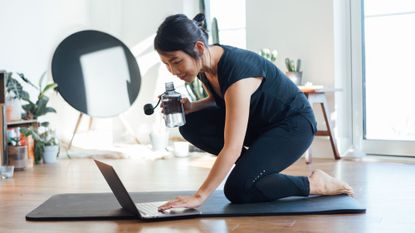 Simple home workouts: A woman loading a workout on her laptop at home