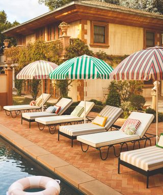 italian style villa with poolside loungers in a retro vintage style with striped patio umbrellas