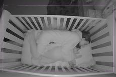 Mum asleep with her baby, both in the cot together