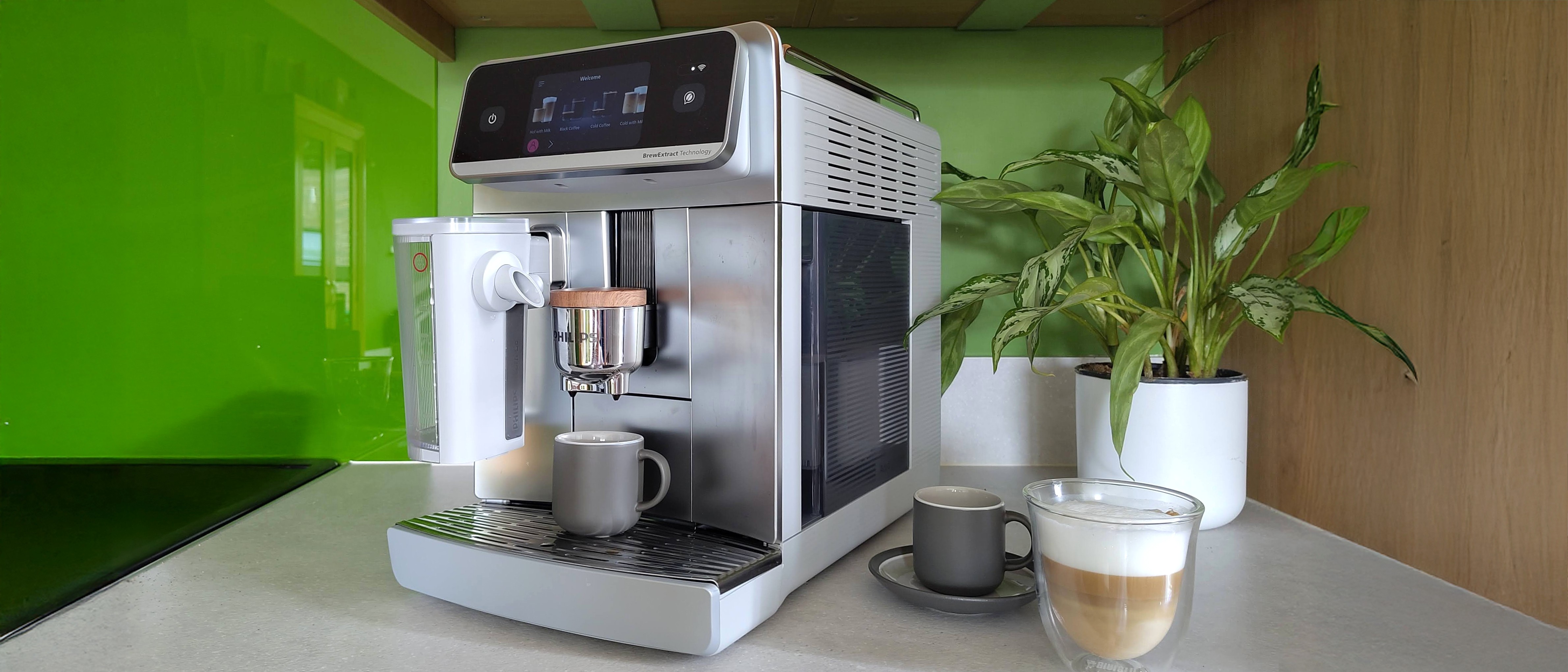 Philips Cafe Aromis 8000 Series coffee maker on kitchen counter with cups of coffee and house plant