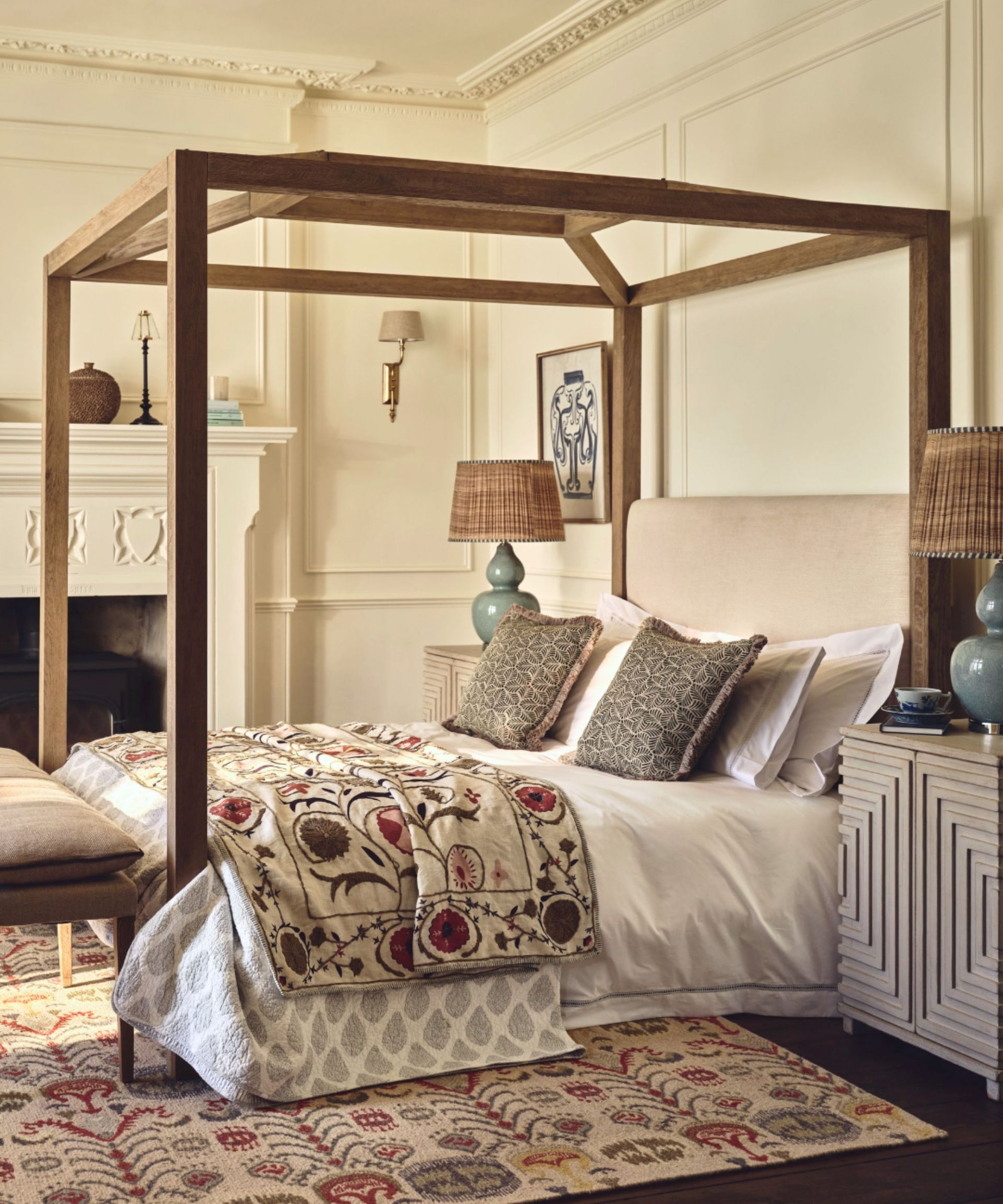 Oka bedroom with a wooden four poster bed, suzani throw and statement table lamps