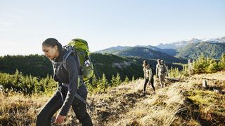 三个女人徒步走在一条以山为背景的小径上