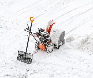 Snow blower machine and shovel on snowy background