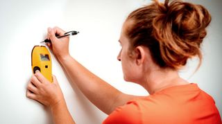 Women holding a stud detector against a wall