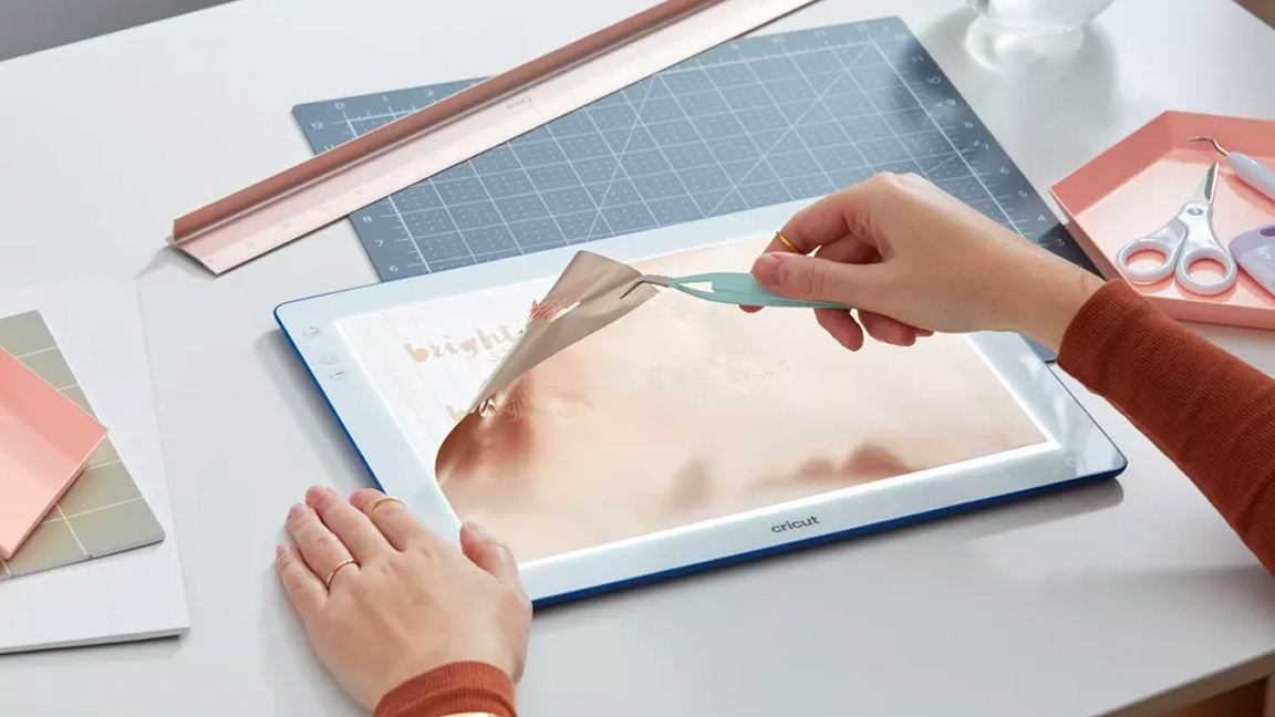 A lightbox is on a table, a person peels back some material