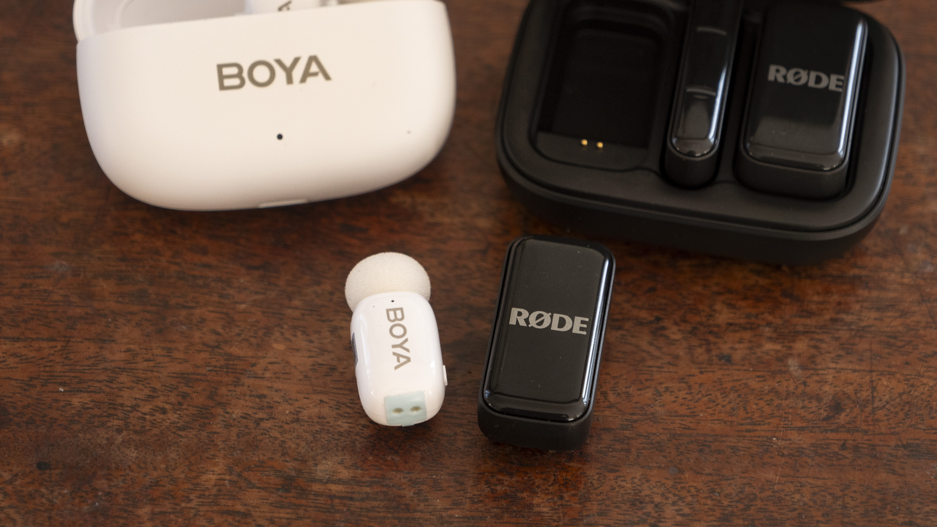 Boya Mini wireless mic alongside the Rode Wireless Micro on a mahogany side