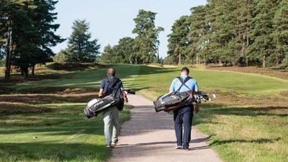 Golfers walk on a path leading to the fairway