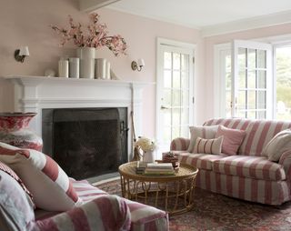 fireplace with white surround and pink walls as well as pink and white striped sofas