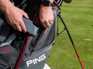 man putting phone in golf bag