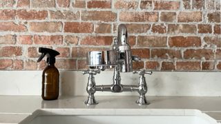 tap filter fitted to swan neck chrome kitchen tap with brick wall background