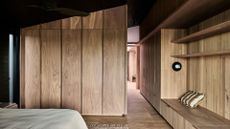 A spacious bedroom with a focus on wood-led design, including shelving, cupboards and a seating nook