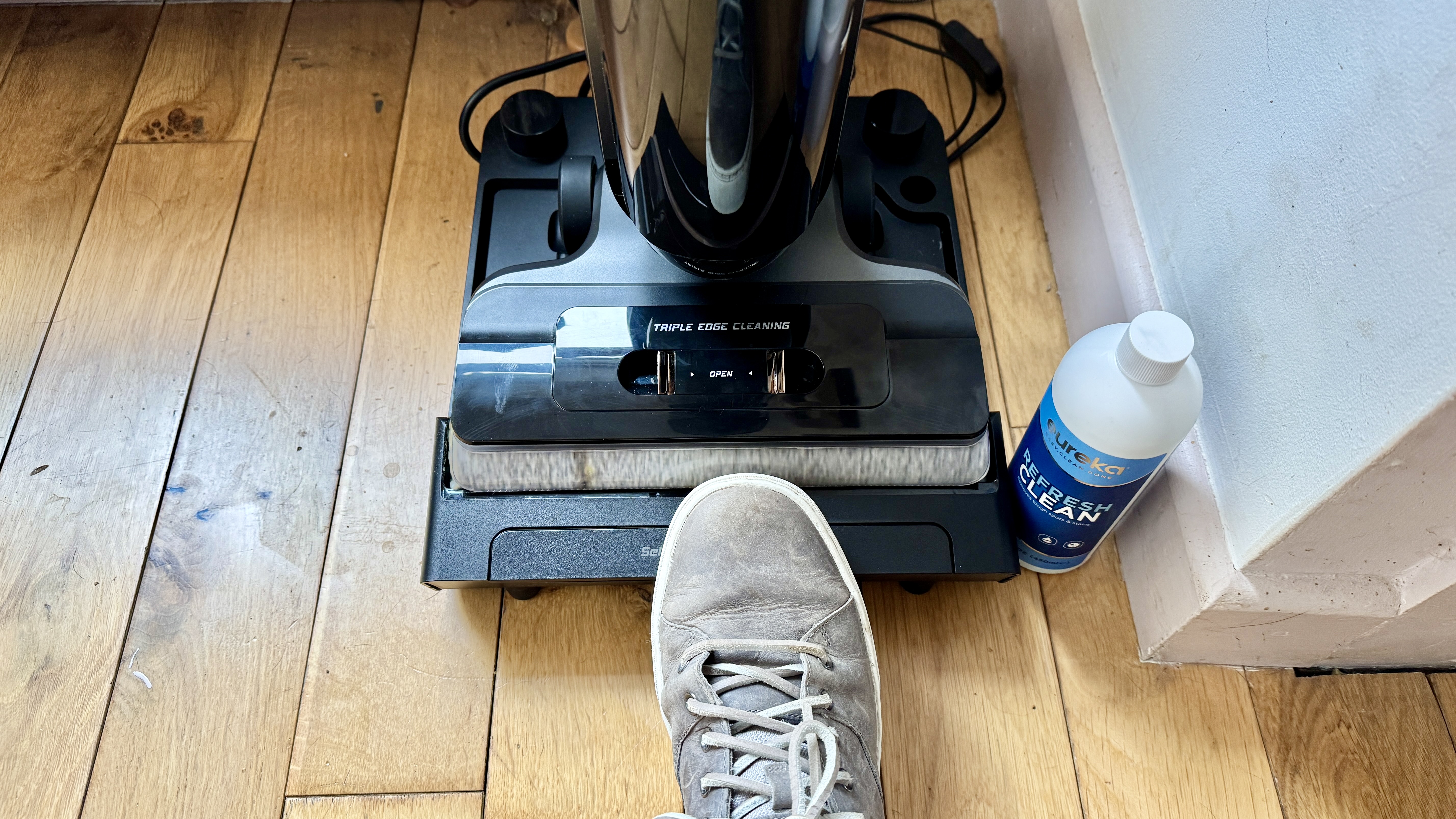 Tester pressing on the bar on Eureka RapidWash 730&#039;s base to activate self-clean