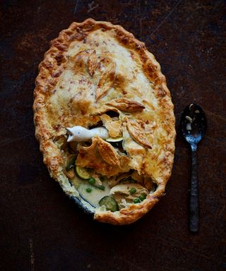 Birds eye view of an oval shaped pie dish with a white ceramic bird in the centre to allow the steam out