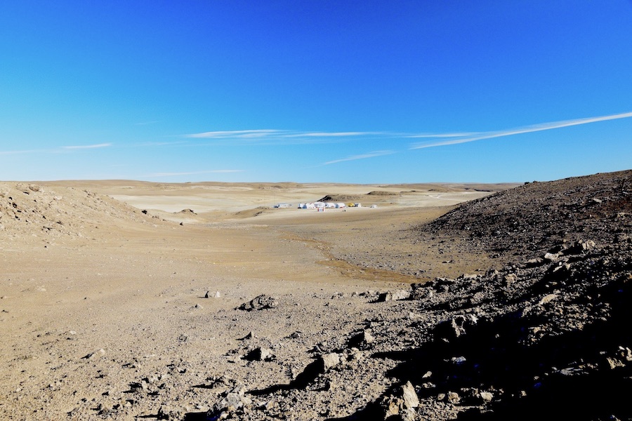 A series of tents belonging to the Haughton-Mars Project can be seen in the distance above a bleak Arctic landscape.