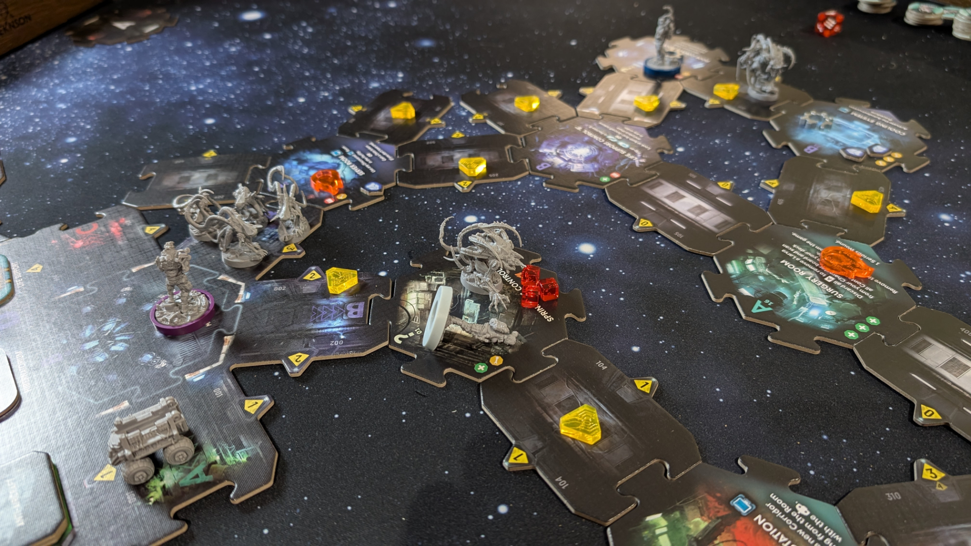 Nemesis: Retaliation pieces, board tiles, and tokens on a gaming table with a starry effect