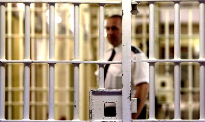A guard looks into a prison cell.