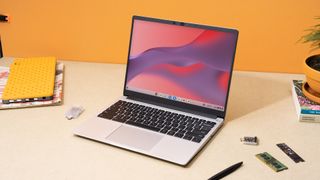 Framework laptop Chromebook edition on a desk with an orange background.
