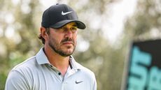 Brooks Koepka wearing a black Nike cap and grey polo