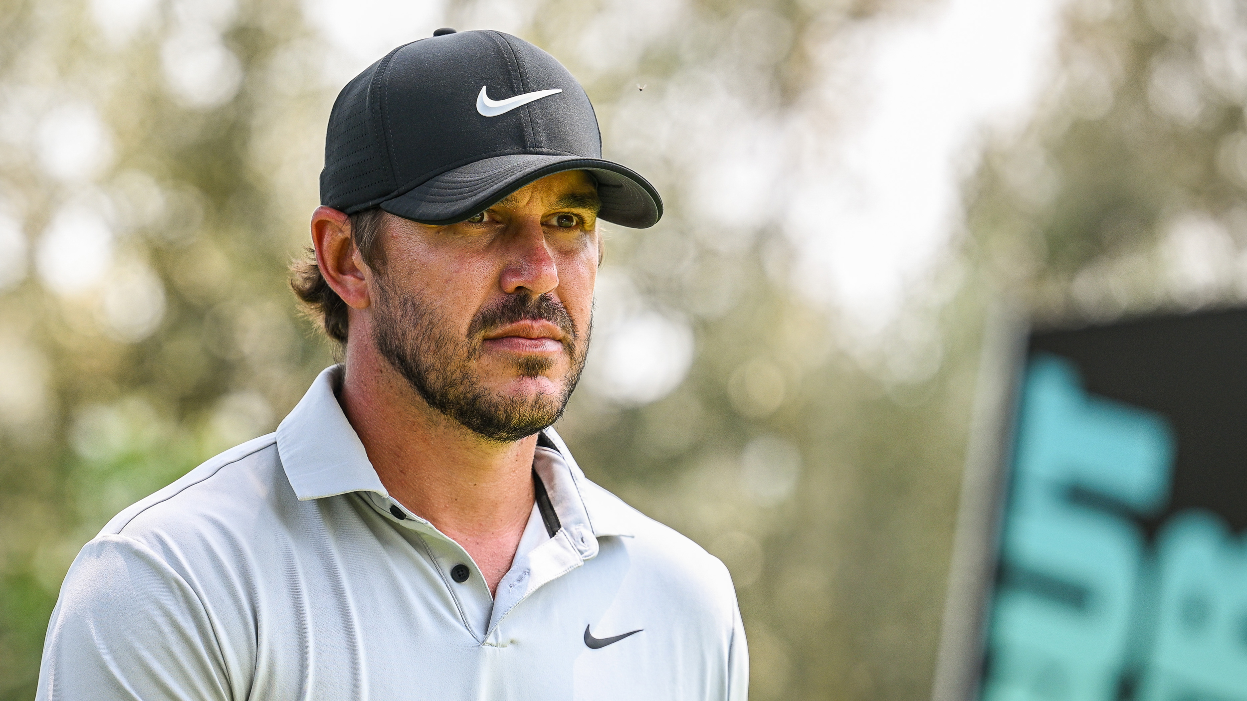 Brooks Koepka wearing a black Nike cap and grey polo