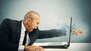 A person getting angry with their laptop and punching through the screen