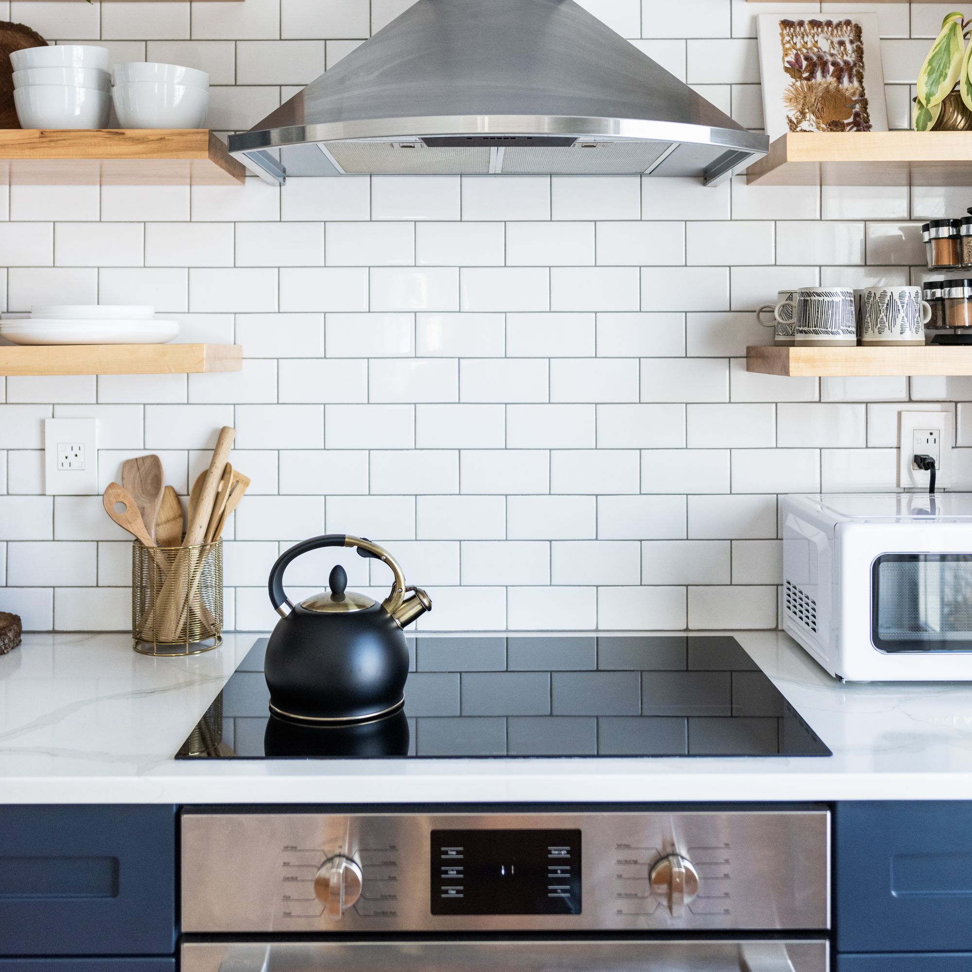 kitchen hob with black stovetop kettle in front of white tiled wall