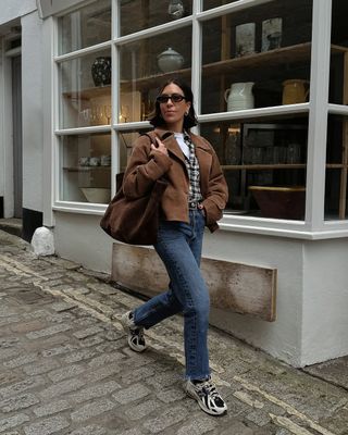 Jessica in a cropped brown jacket, jeans and trainers