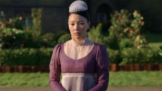 Sophie, played be Yerin Ha, in a full purple maid costume standing outside in Bridgerton Season 4. 