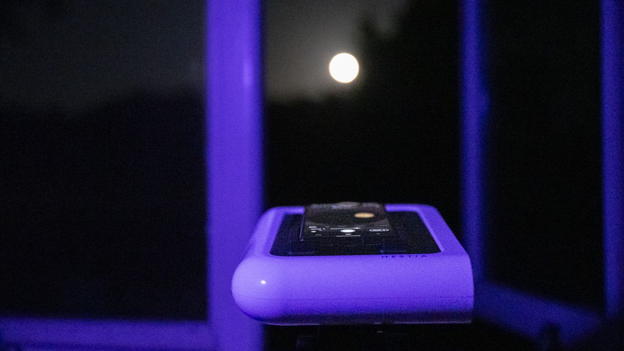 Vaonis Hestia smart telescope on a tripod pointing up at the night sky with a Google Pixel phone attached