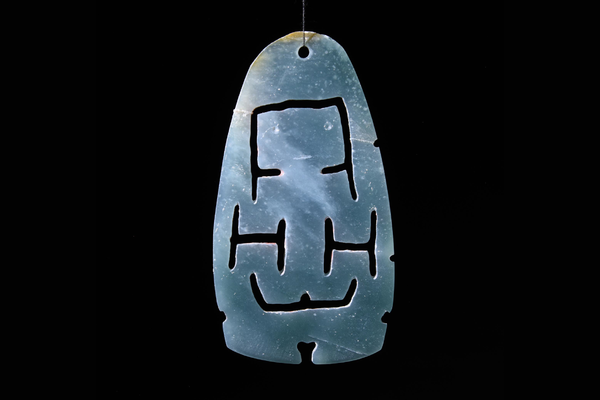 a jade ornament with geometric carvings
