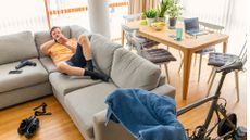 Image shows a cyclist on the sofa instead of riding his bike