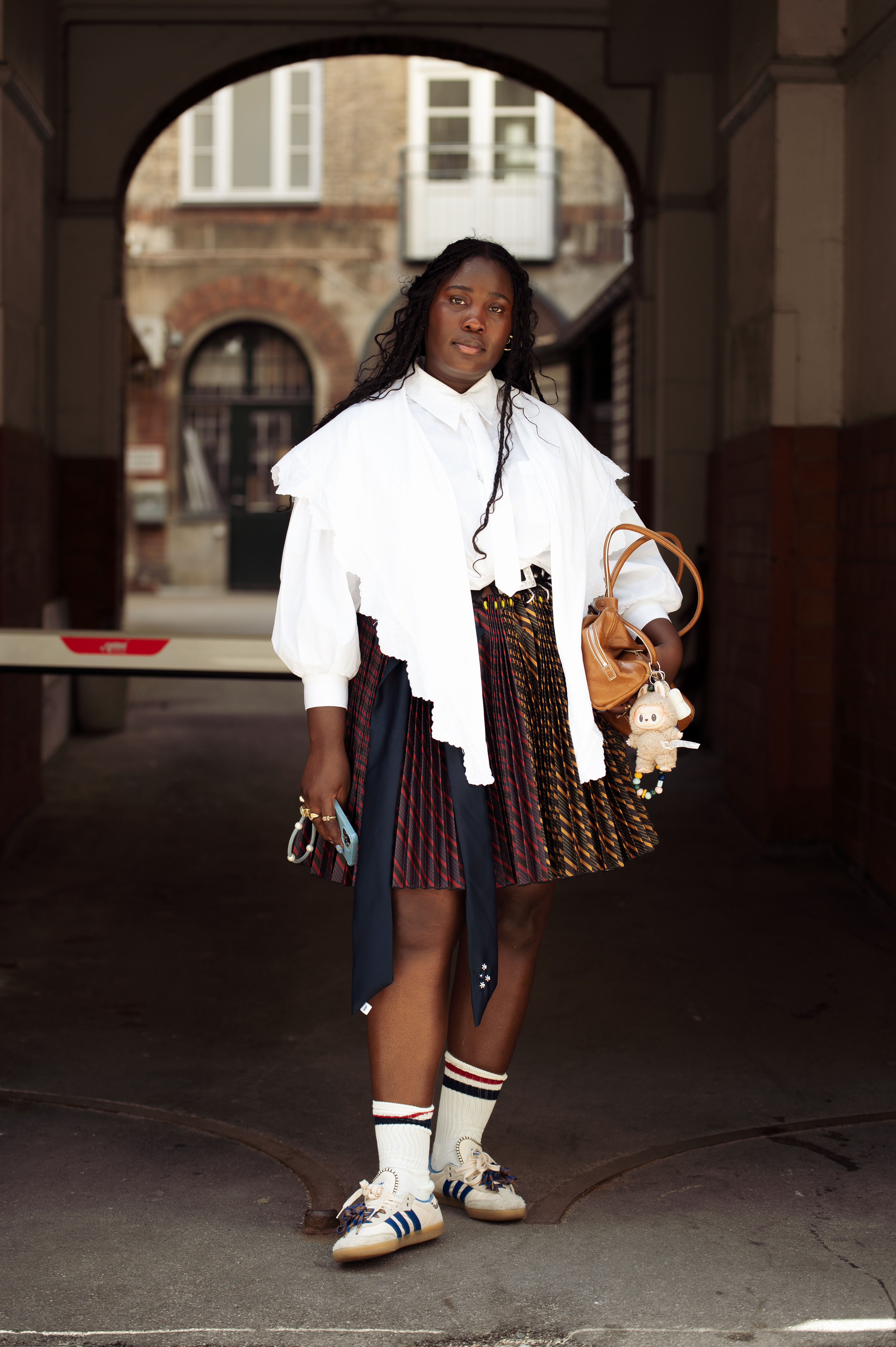 woman wearing white blouse, brown skirt, and adidas sambas