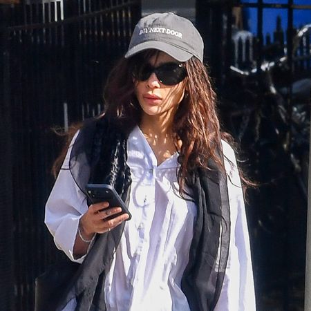 Zo&euml; Kravitz wearing a sheer skinny scarf, white button-down shirt, black pants, and black Adidas Samba sneakers