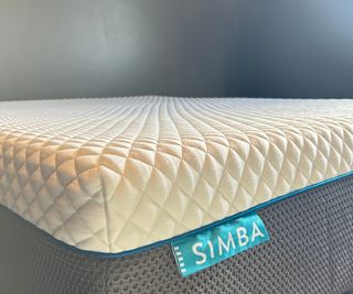 Corner of the Simba Hybrid Pro Mattress against a dark green wall.