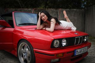 Canon EOS R1 sample image: a female model posing with a red BMW