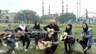 A group of Afghan girls playing acoustic guitars