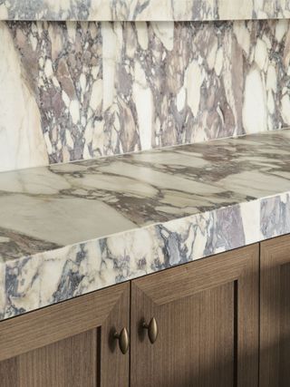 A richly veined marble has a honed edge finish, on top of wooden cabinetry