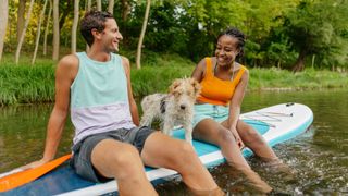 Couple paddleboarding with dog