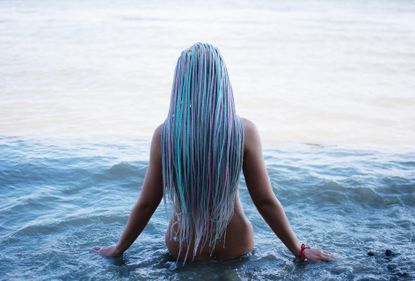 Rear View Of Naked Woman With Colorful Long Hair Standing In Sea - stock photo