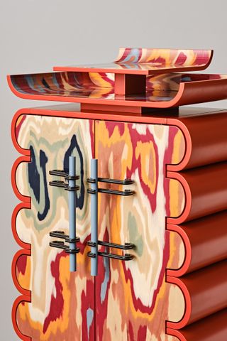 Close-up view of colourful wooden cabinet in shades of orange, blue and yellow.