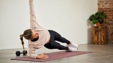 A woman performing a side plank as part of a full-body workout at home 