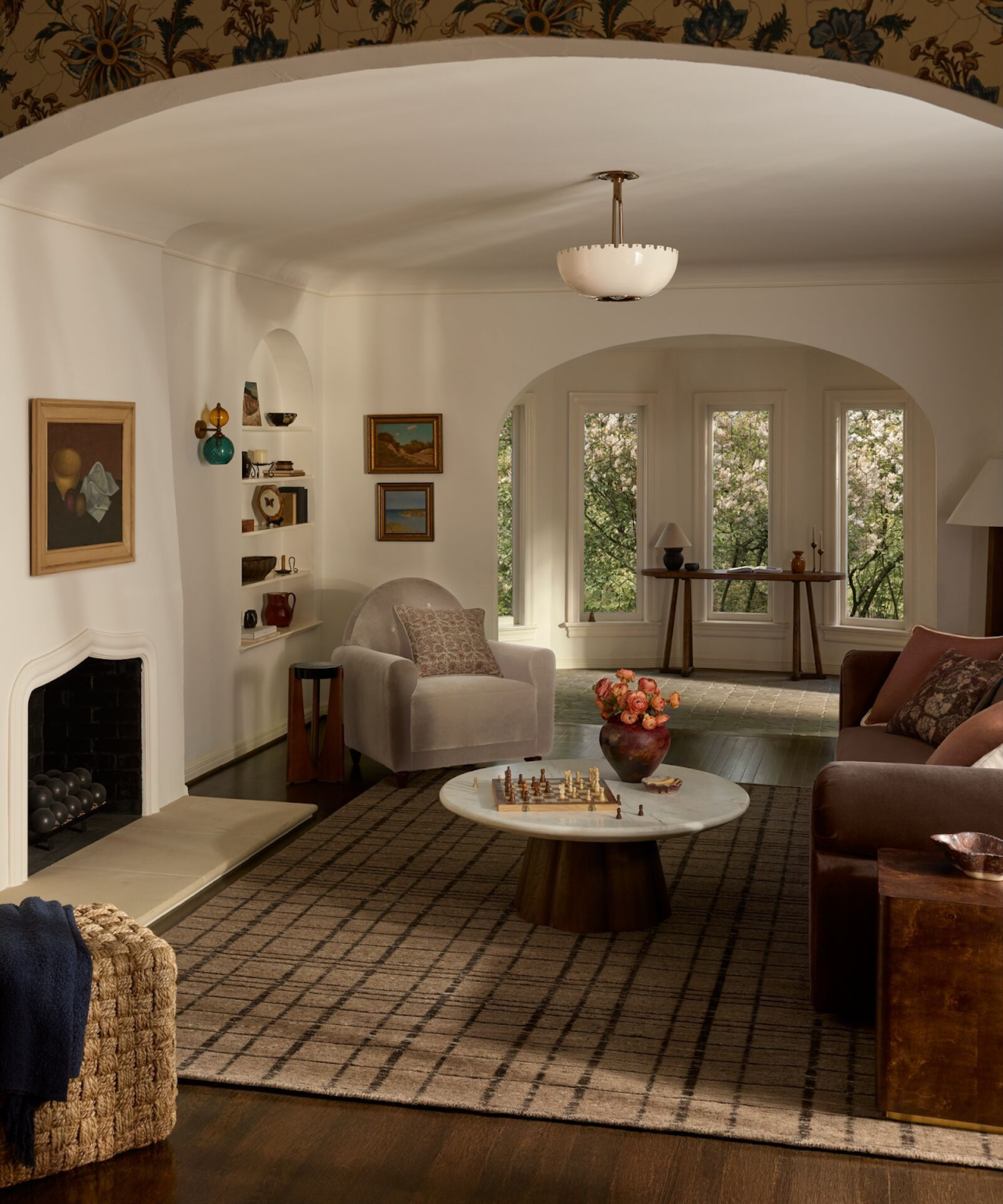 a warm living room with a striped rug, a coffee table with a marble top, white-painted walls, a gray accent chair, and a large brown couch